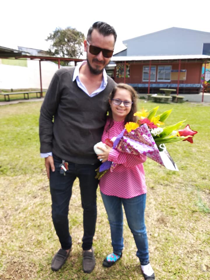 Profesor de la institución con estudiante y unas flores